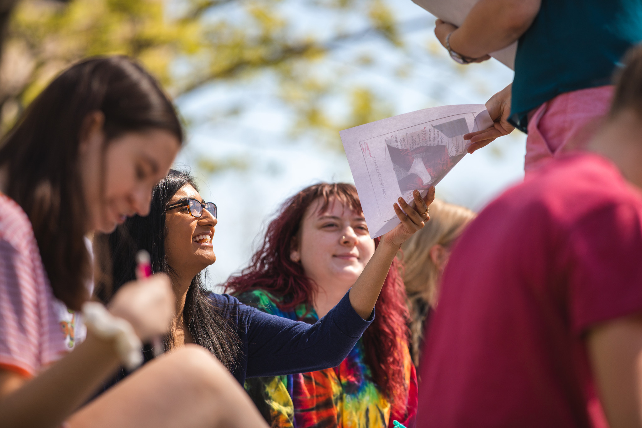 Students studying outside, one student handing in paper or assignment